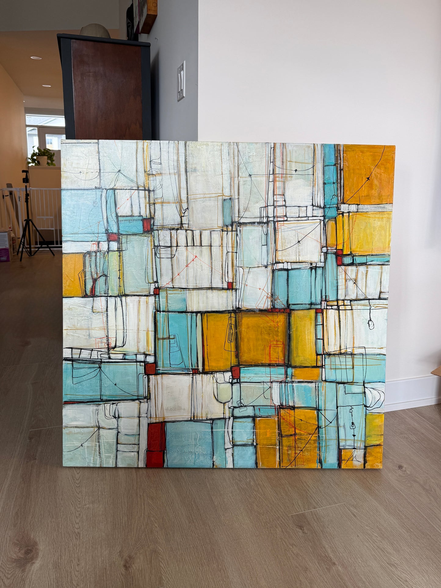 Abstract art piece with geometric shapes on a wall in a room.