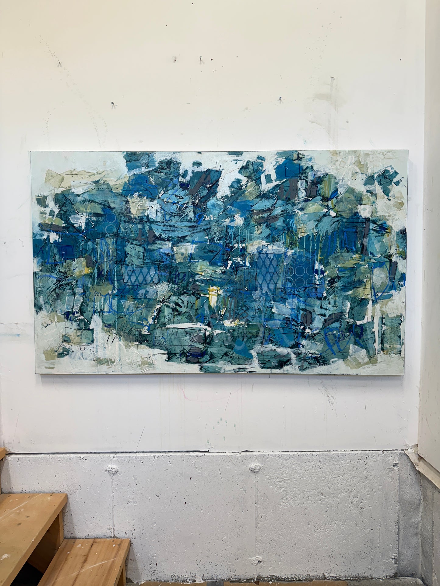 Large 48 x 72 inch abstract acrylic painting on canvas by Canadian artist Lori Mirabelli, featuring layered shades of deep and muted blue with hints of green, white, and texture, displayed above a cozy white bed with soft blue bedding in a modern minimalist bedroom. Contemporary fine art by Toronto-based abstract painter Lori Mirabelli, collected in homes across Canada and the U.S.