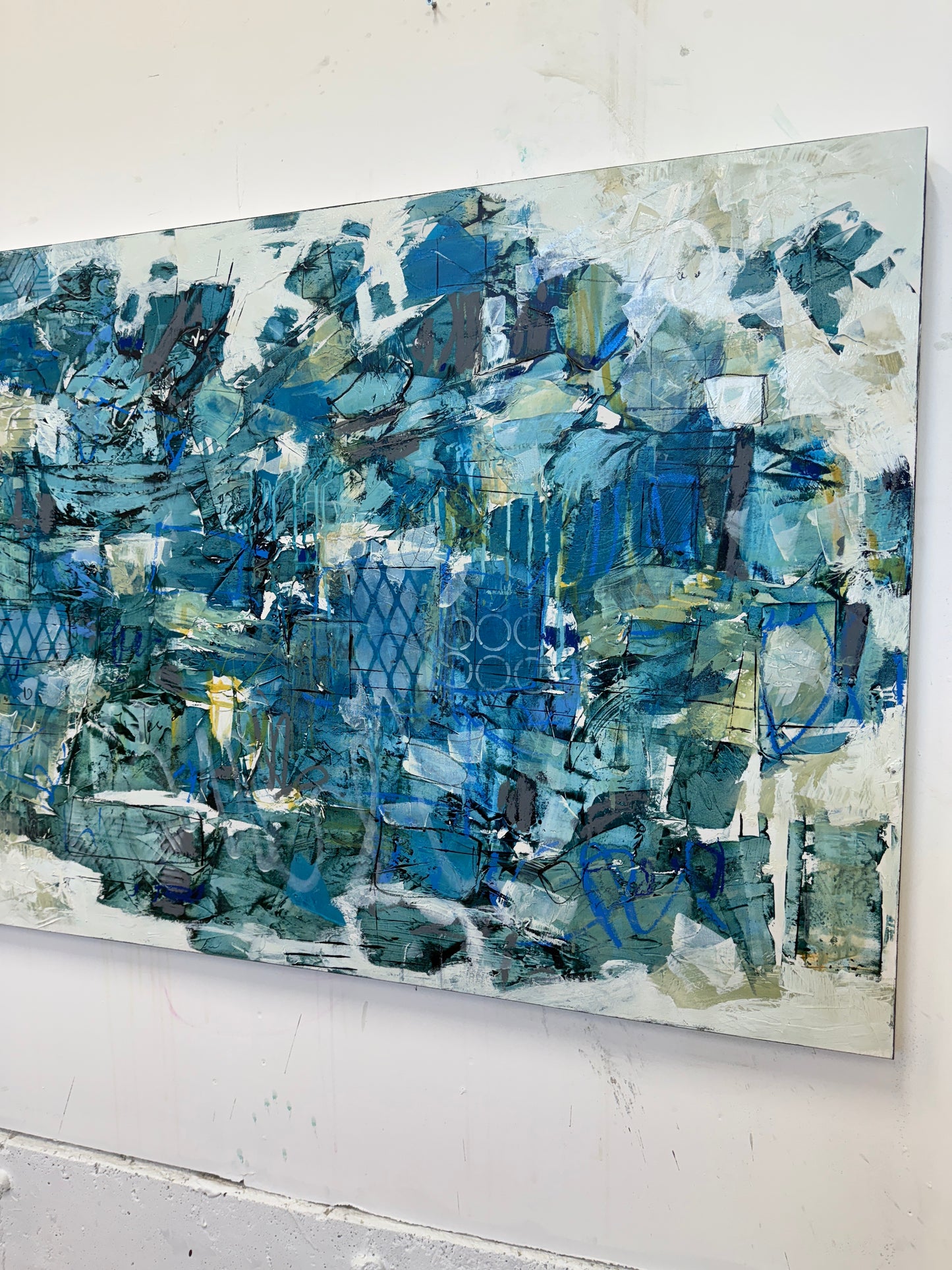 Large 48 x 72 inch abstract acrylic painting on canvas by Canadian artist Lori Mirabelli, featuring layered shades of deep and muted blue with hints of green, white, and texture, displayed above a cozy white bed with soft blue bedding in a modern minimalist bedroom. Contemporary fine art by Toronto-based abstract painter Lori Mirabelli, collected in homes across Canada and the U.S.