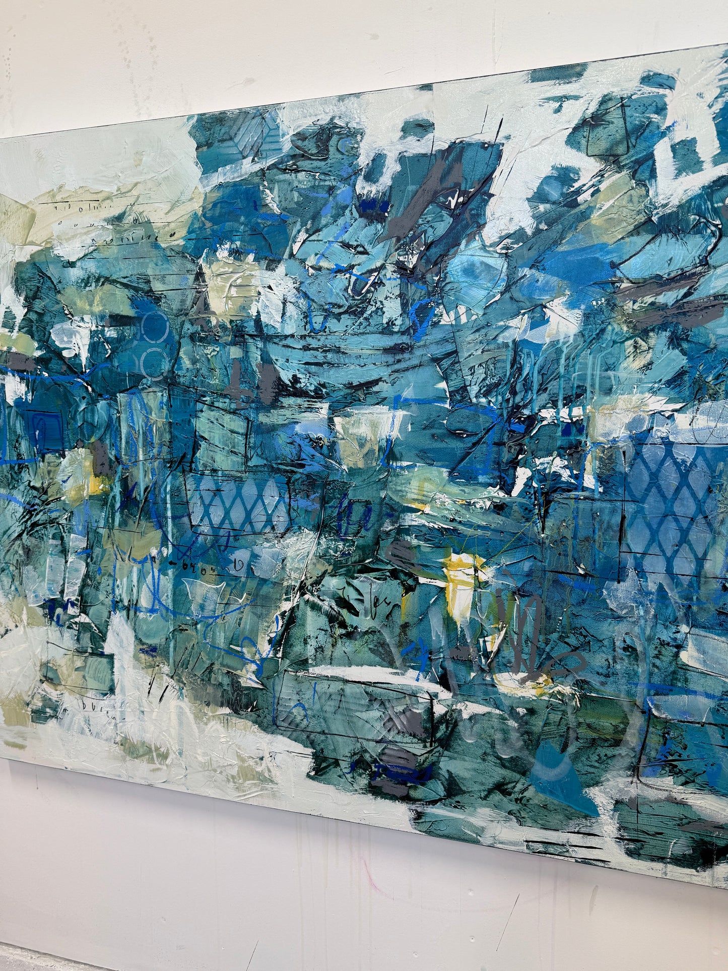 Large 48 x 72 inch abstract acrylic painting on canvas by Canadian artist Lori Mirabelli, featuring layered shades of deep and muted blue with hints of green, white, and texture, displayed above a cozy white bed with soft blue bedding in a modern minimalist bedroom. Contemporary fine art by Toronto-based abstract painter Lori Mirabelli, collected in homes across Canada and the U.S.