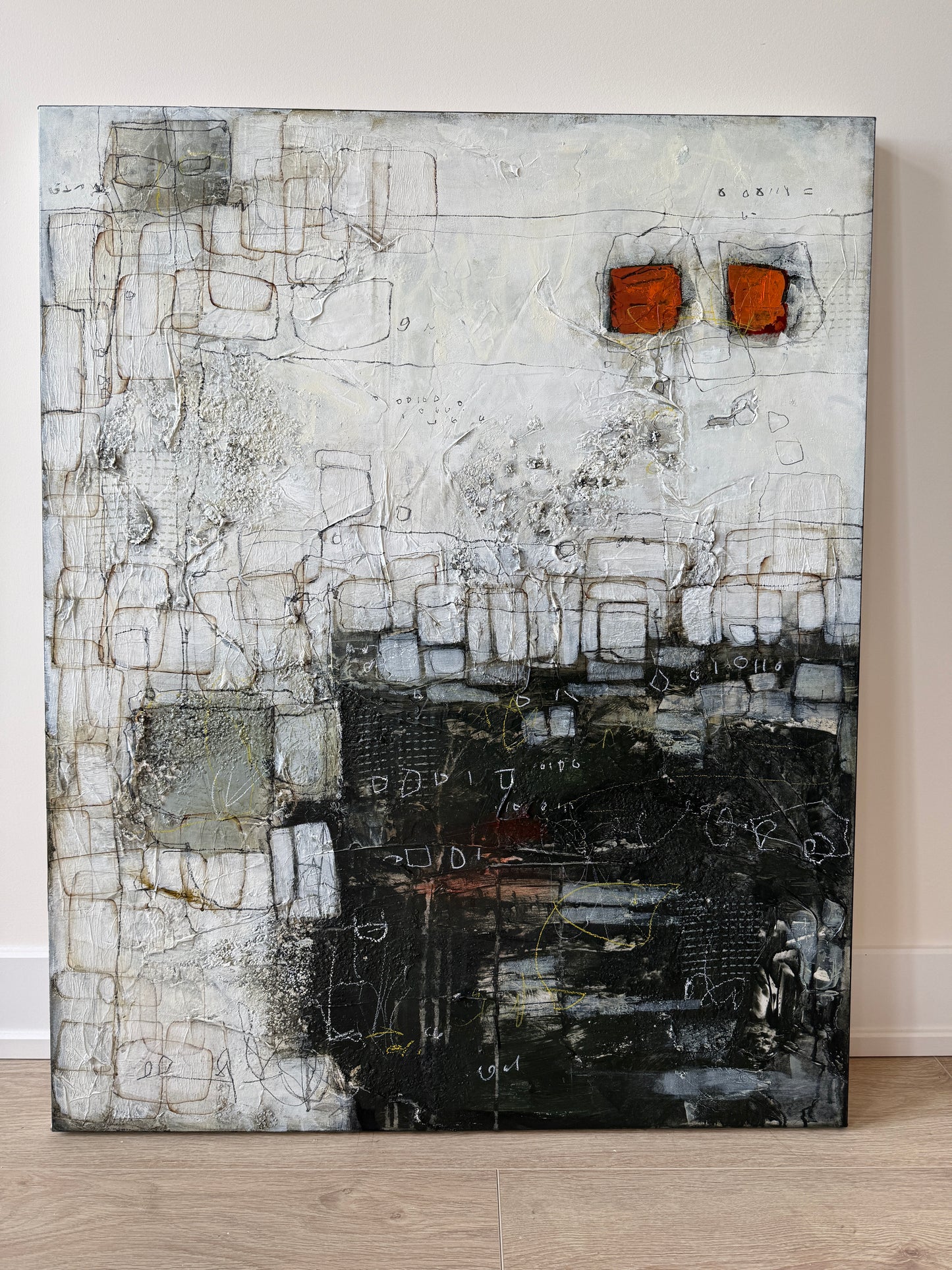 Abstract art piece with textured surface on a light wood floor