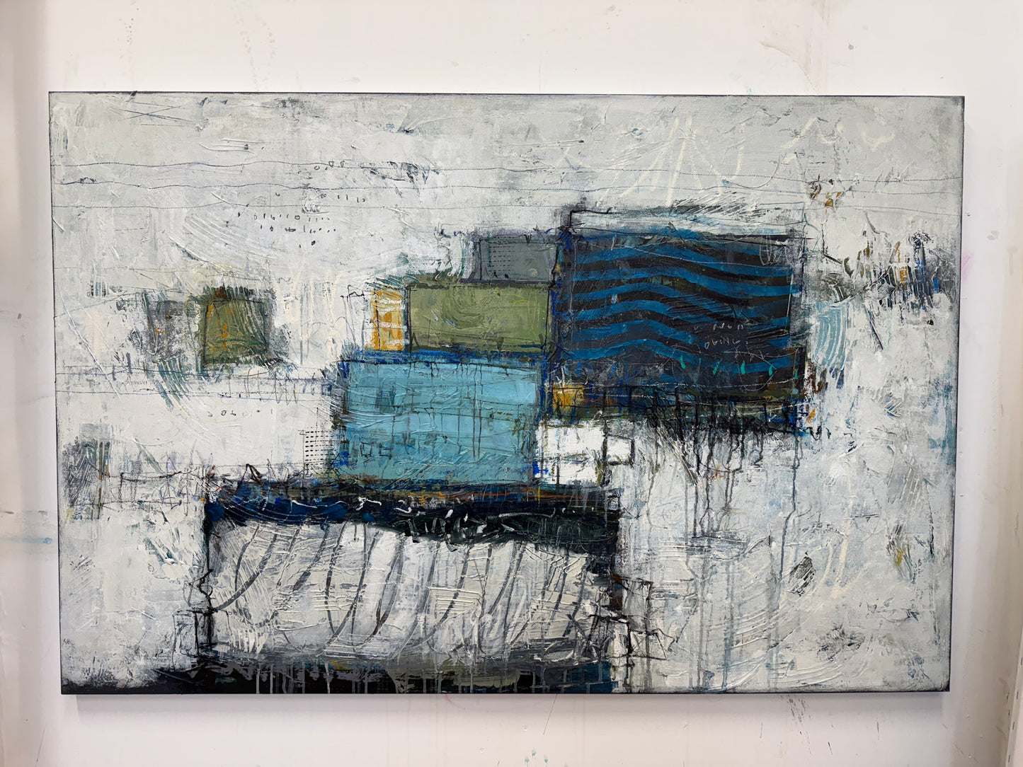 Abstract painting with blue and gray tones on a white wall