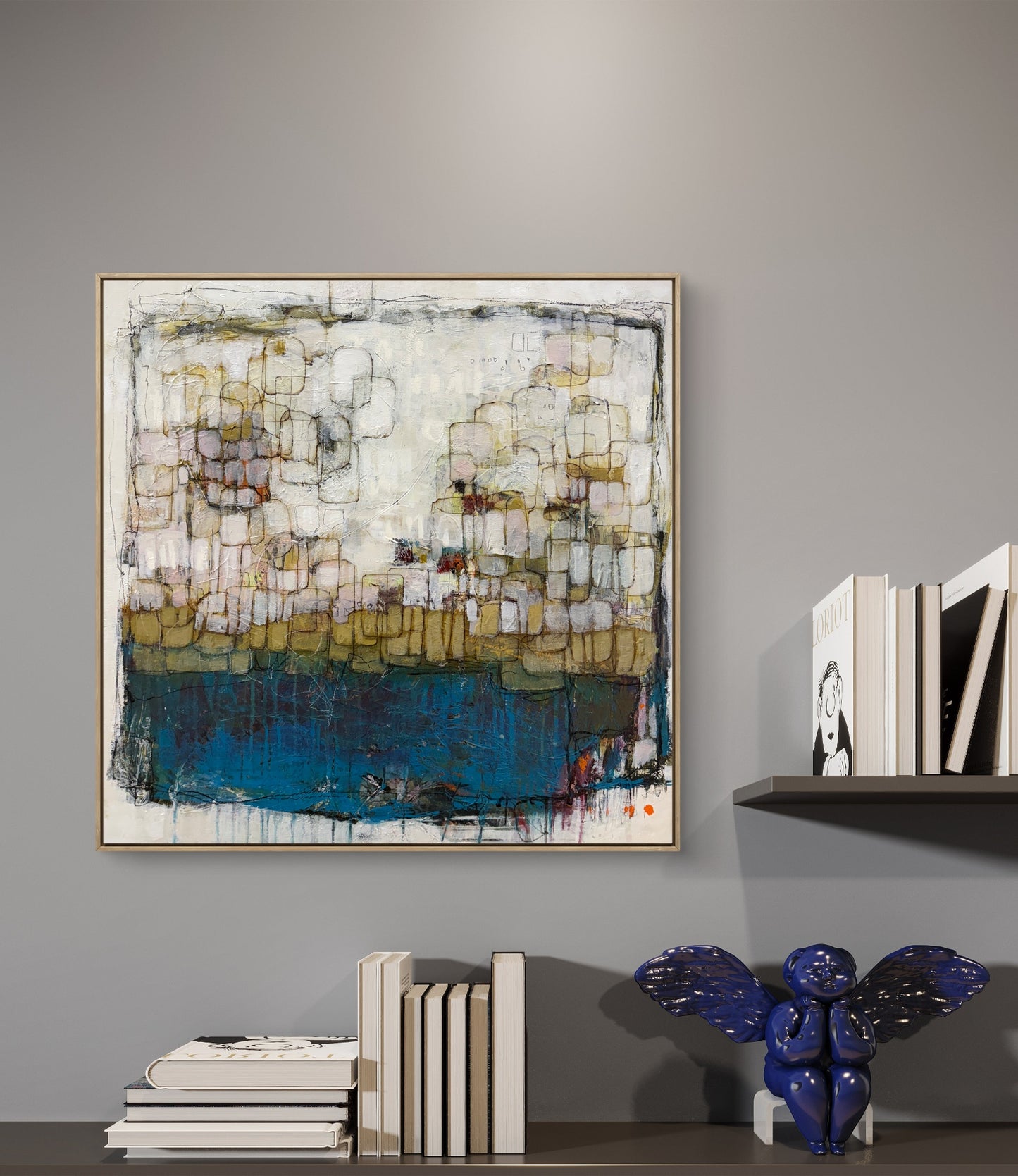 Abstract painting on a gray wall with books and a decorative vase below.