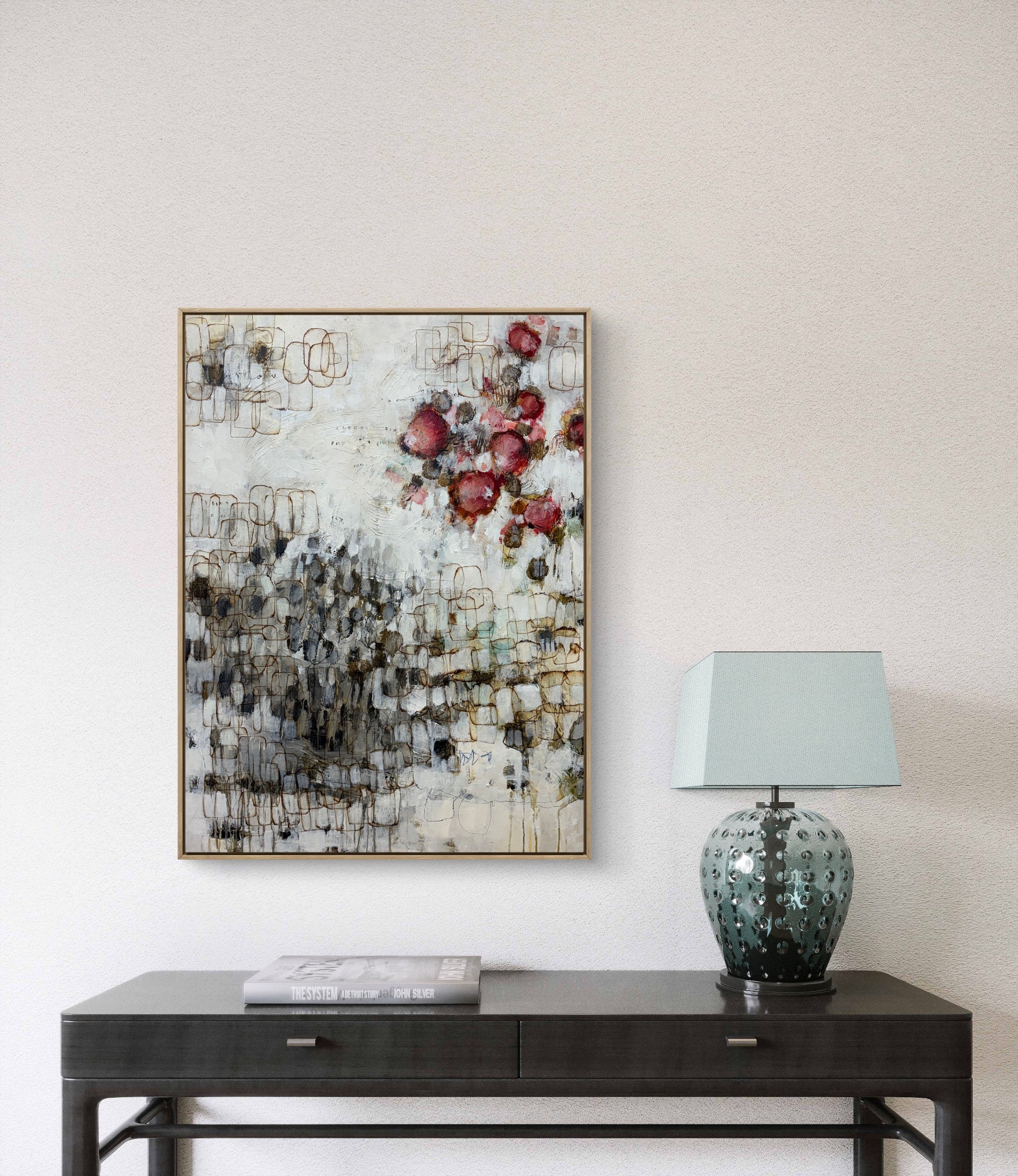 Abstract floral painting on a wall above a dark wooden console table with a lamp.