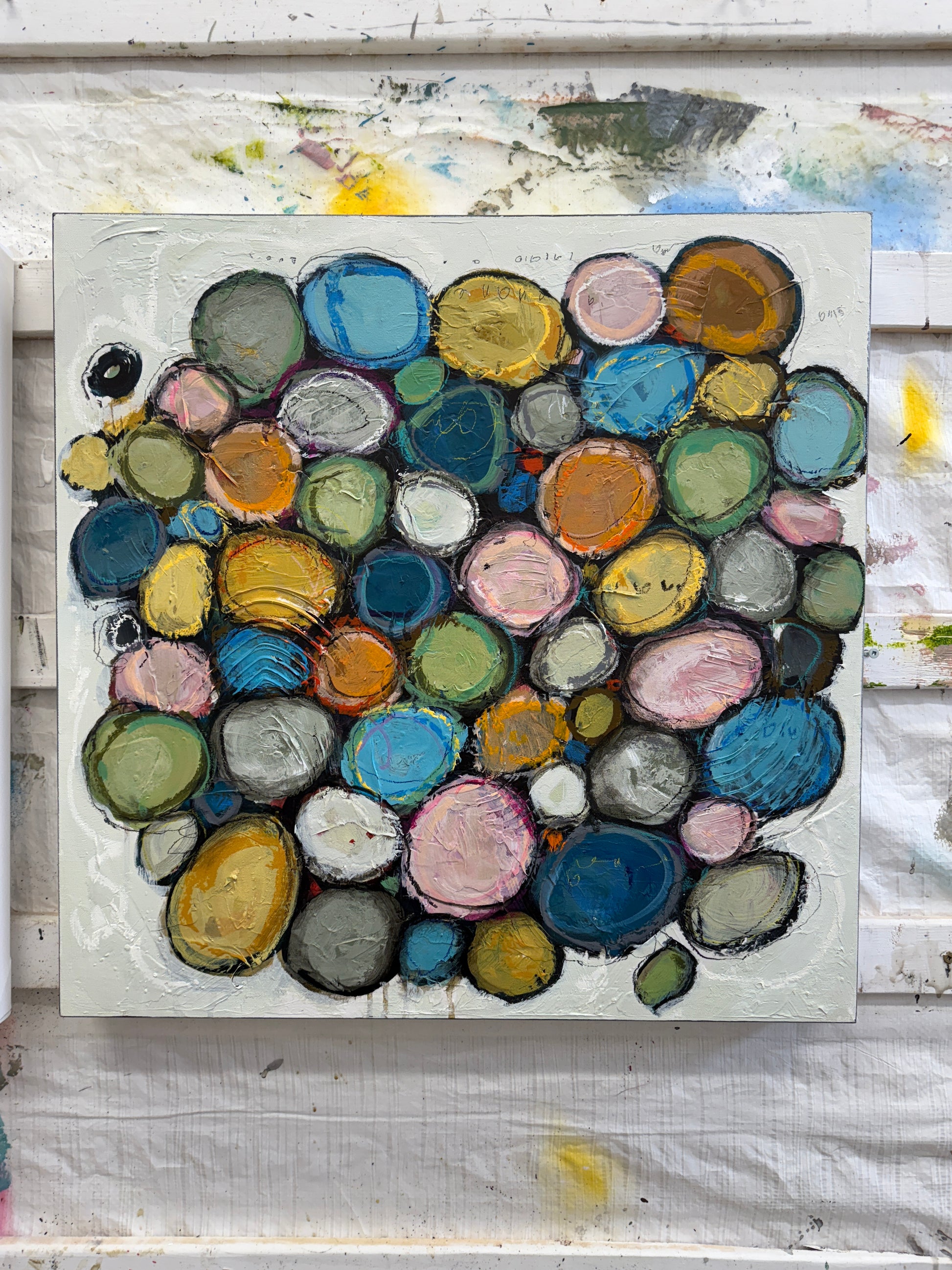 Contemporary abstract acrylic painting on canvas featuring layered colourful circular forms in soft blue, pink, green, gold, and neutral tones, surrounded by textured white space with expressive mark making and organic composition.
