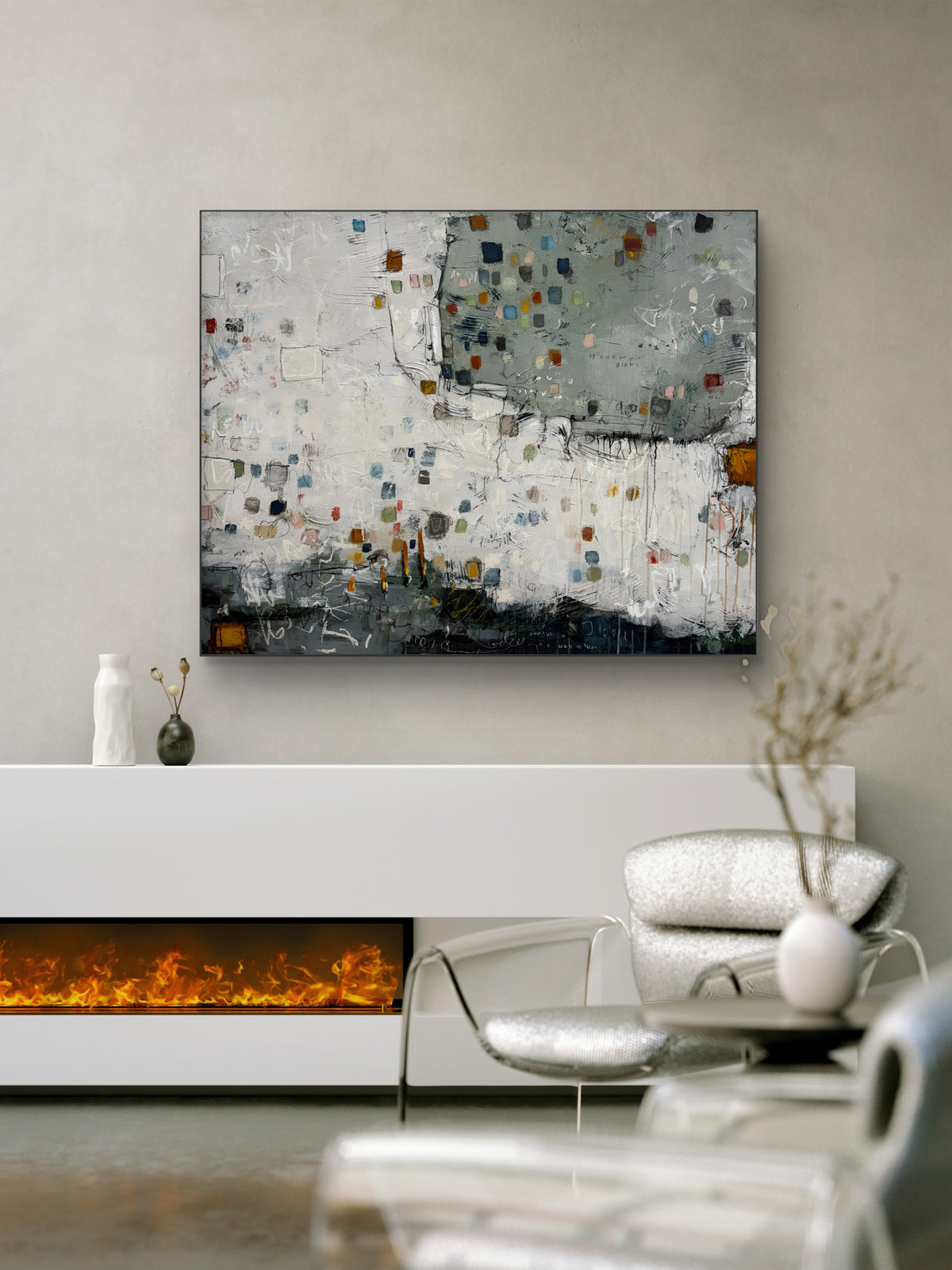 Large 48 × 60-inch abstract painting with textured white and sage-grey fields, scattered small squares in blue, mustard, rust, pink and green, and loose black and white lines. Dark charcoal layers anchor the bottom edge. The painting hangs above a black leather chair with wooden arms against a light wall.