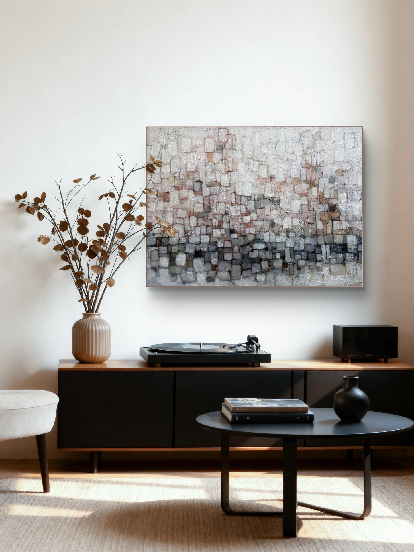 An abstract canvas wall art print featuring a textured mosaic of gray, white, and beige blocks, displayed in a modern living room setting above a black media console.