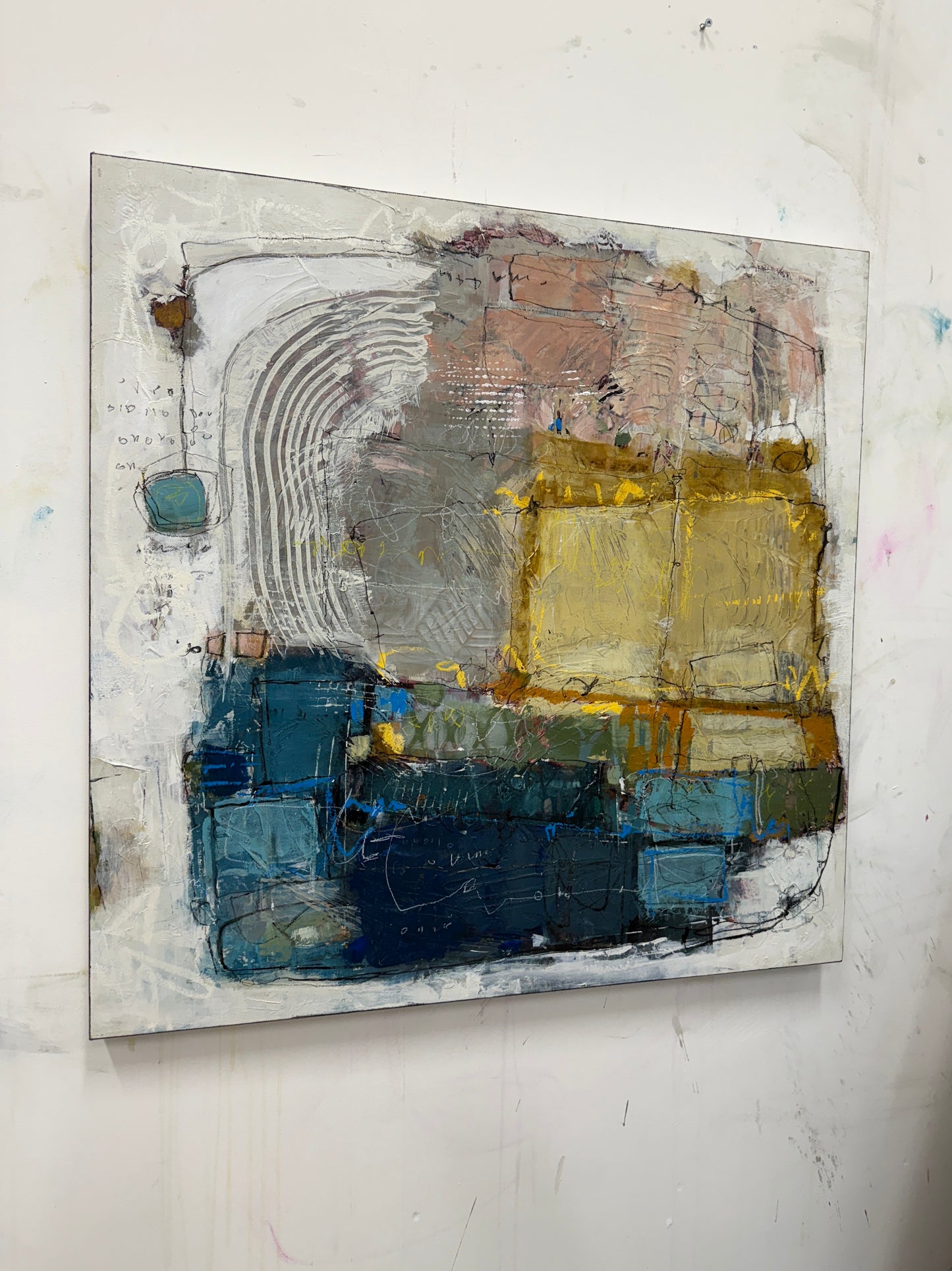 Abstract art piece with blue, gold, and gray tones on a white wall.