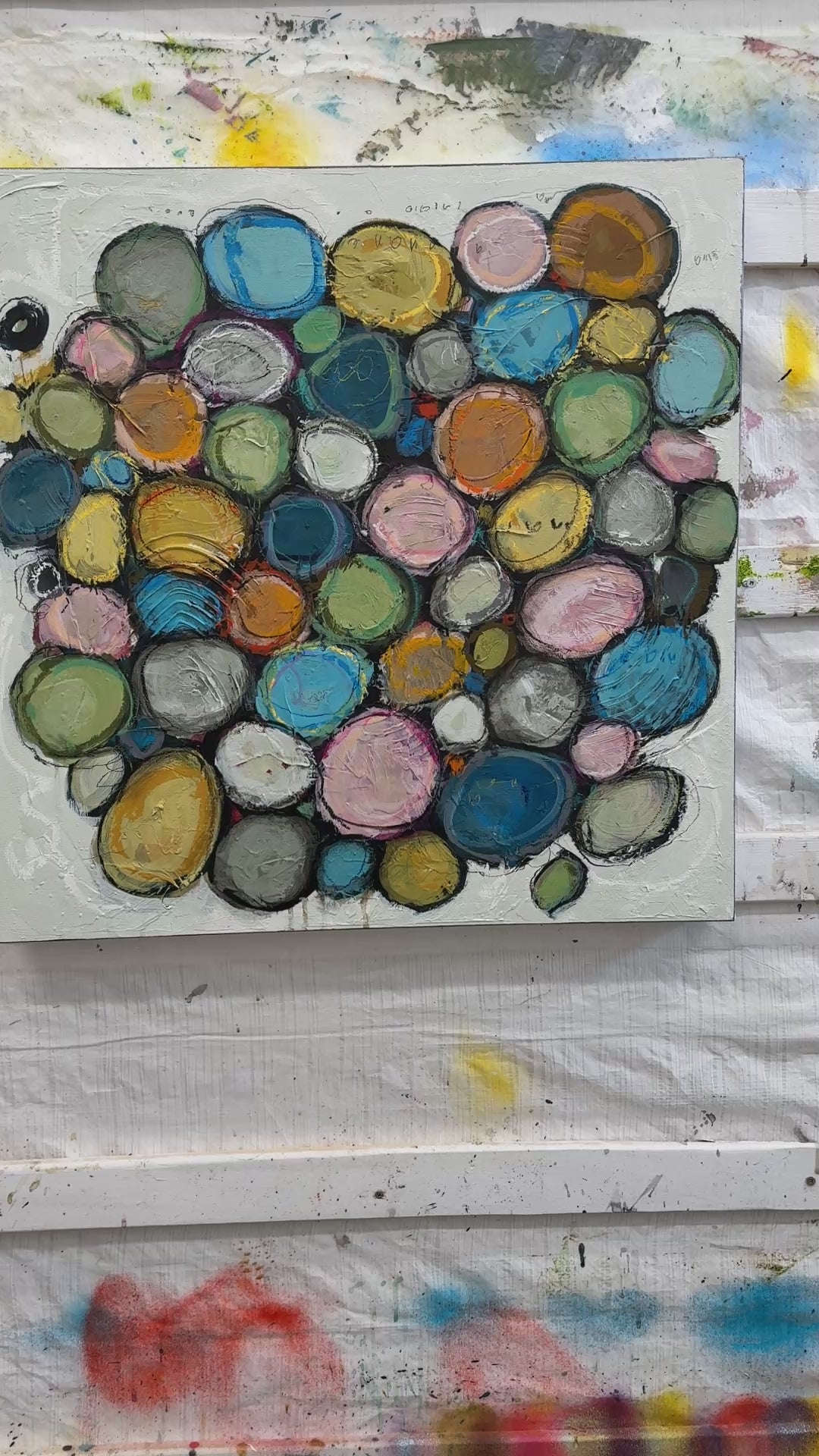 Contemporary abstract acrylic painting on canvas featuring layered colourful circular forms in soft blue, pink, green, gold, and neutral tones, surrounded by textured white space with expressive mark making and organic composition.